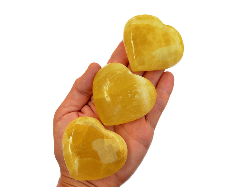 Three lemon yellow calcite heart crystals 55mm on hand with white background
