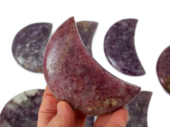 One refd pink lepidolite moon 90mm on hand with background with some specimens on white