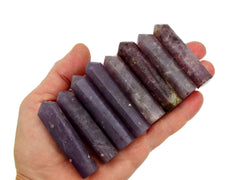 Eight purple lepidolite faceted crystal points 50mm-55mm on hand with white background