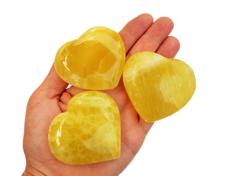 Three lemon calcite heart minerals 55mm-65mm on hand with white background