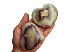 Two pink banded onyx heart stones 75mm-80mm on hand with white background