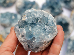 Chunky raw blue celestite crystal  70mm on hand with background with some stones