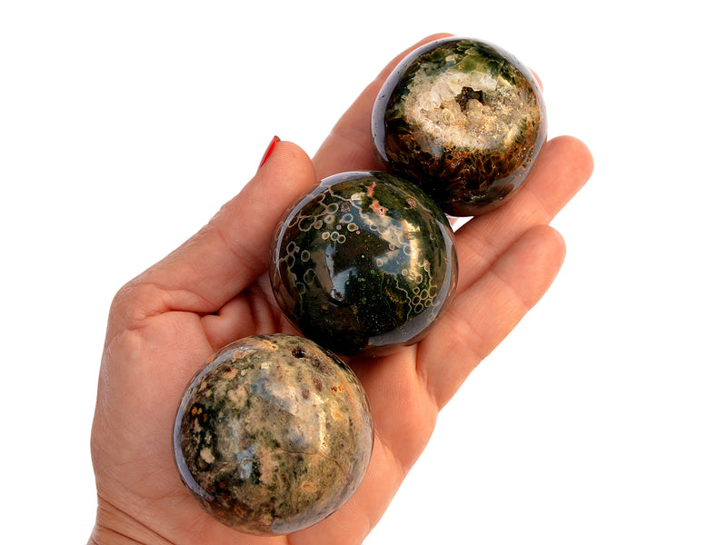 Three ocean jasper sphere minerals 50mm on hand with white background