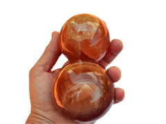 Two honey calcite crystal spheres 65mm on hand with white background