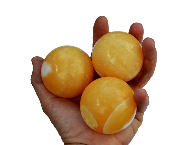 Four orange calcite spheres 55mm-60mm on hand with white background