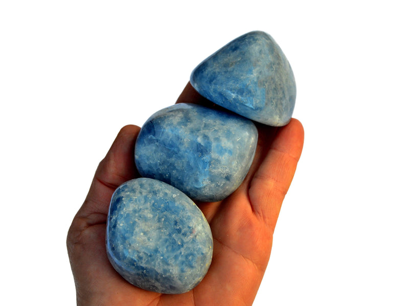 Three large blue calcite tumbled minerals on hand with white background