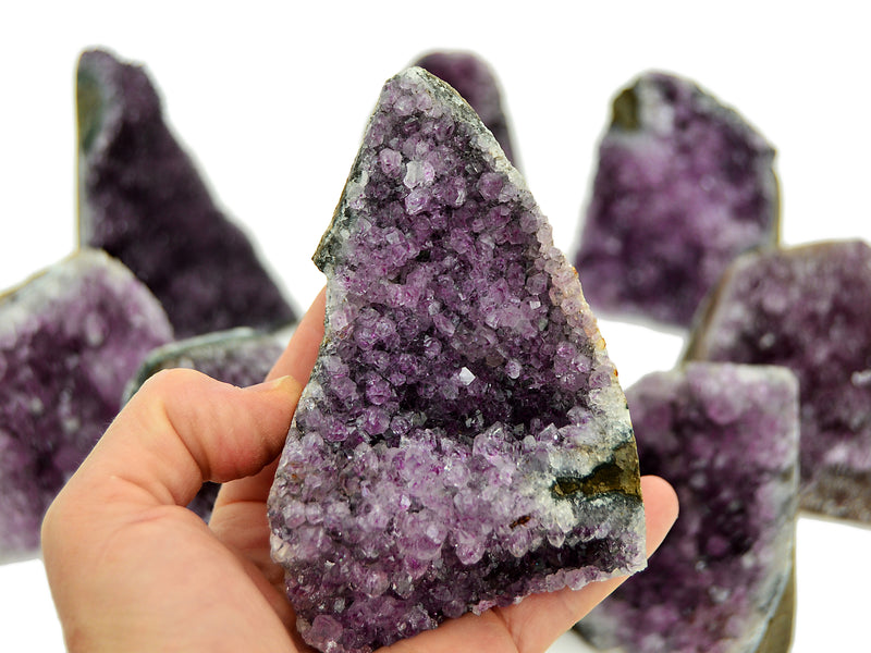 One purple amethyst cluster cut base 90mm on hand with background with some crystals