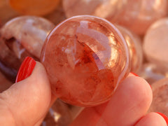 One hematoid quartz crystal sphere 30mm on hand with background with several spheres