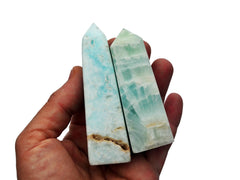 Two small blue caribbean calcite obelisks on hand with white background