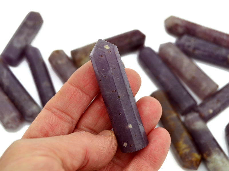 One purple lepidolite point 55mm on hand with background with some points on white