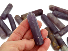One purple lepidolite point 55mm on hand with background with some points on white