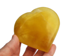One lemon calcite heart stone 80mm on hand with white background 