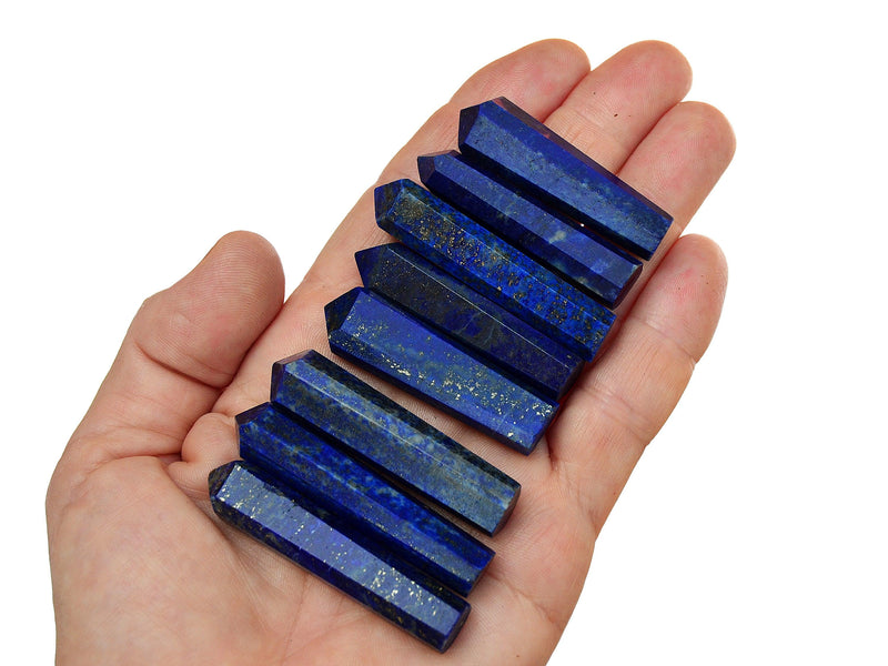 Eight blue lapis lazuli faceted crystal points 45mm-50mm on hand with white background