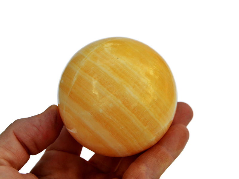 One orange calcite crystal ball 55mm on hand with white background