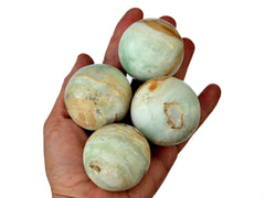 Four caribbean calcite spheres 40mm-50mm on hand with white background