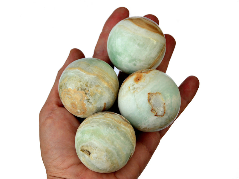 Four caribbean calcite spheres 40mm-50mm on hand with white background