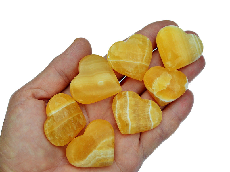 Seven orange calcite hearts 30mm-35mm on hand with white background