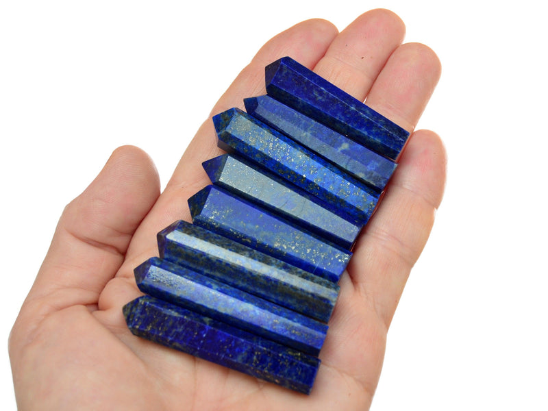 Eight blue lapis lazuli faceted prisms 45mm-50mm on hand with white background