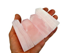 Four pink mangano calcite towers 70mm-75mm on hand with white background