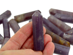 One purple lepidolite crystal point 50mm on hand with background with some points on white