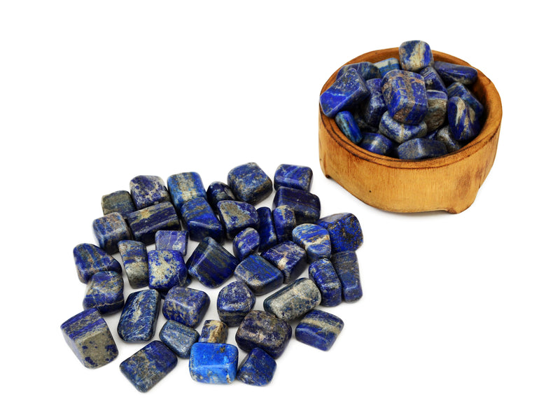 Some lapis lazuli tumbled stones inside a wood bowl and some stones outside on white background