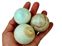 Three caribbean calcite crystal balls 50mm-60mm on hand with white background