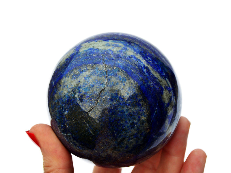 Large blue lapis lazuli crystal sphere 85mm on hand with white background
