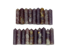 Several purple lepidolite faceted point crystals forming two rows on white background