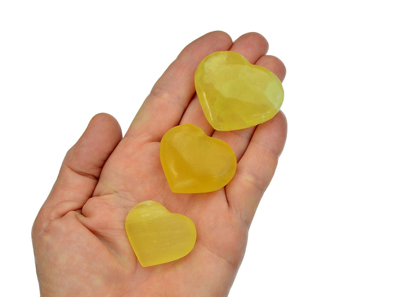 Three lemon calcite heart crystal 25mm-40mm on hand with white background