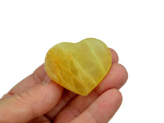 One lemon calcite heart crystal 40mm on hand with white background