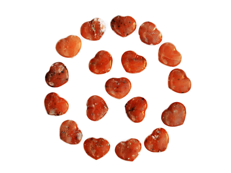 Several orange calcite heart stones 30mm forming a circle on white background