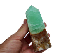 One green pistachio calcite tower 130mm on hand with white background