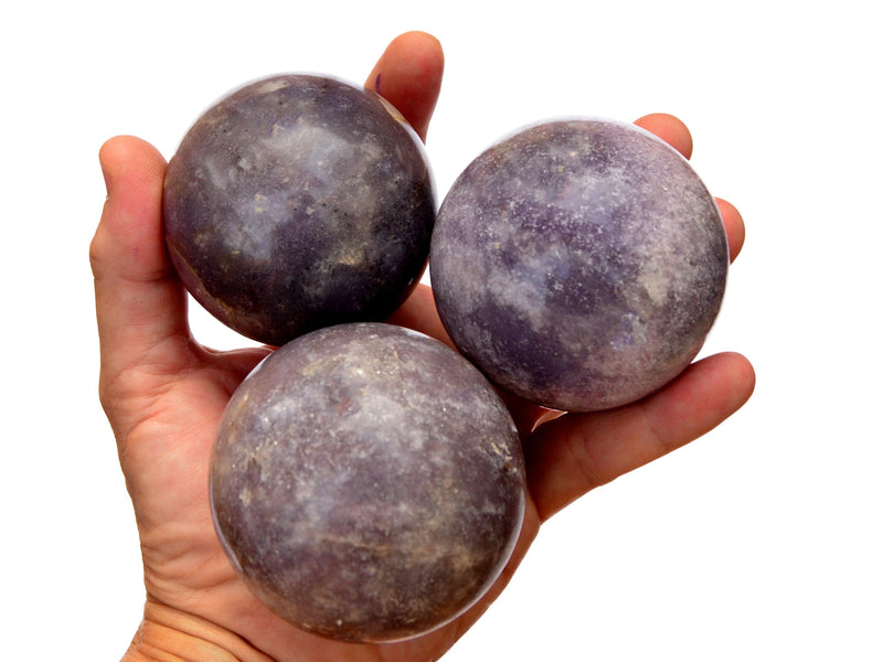 Three lepidolite purple spheres 60mm-65mm on hand with white background