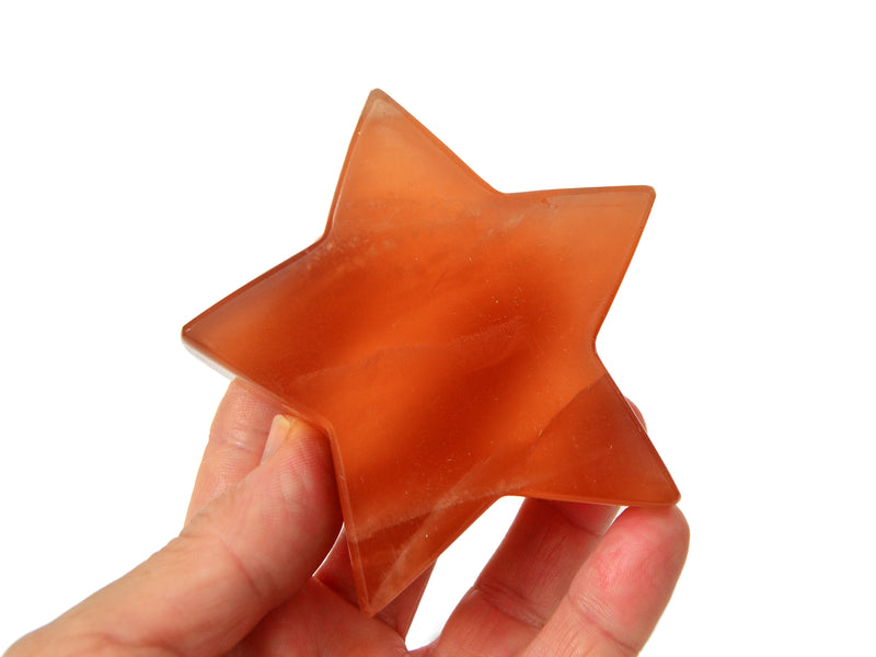 One large honey calcite star 80mm on hand with hite background