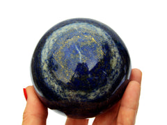 Large lapis lazuli crystal sphere 85mm on hand with white background