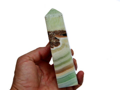 One green banded pistachio calcite point 140mm on hand with white background