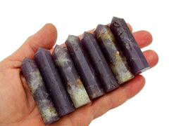 Seven purple lepidolite faceted crystal points 50mm-55mm on hand with white background