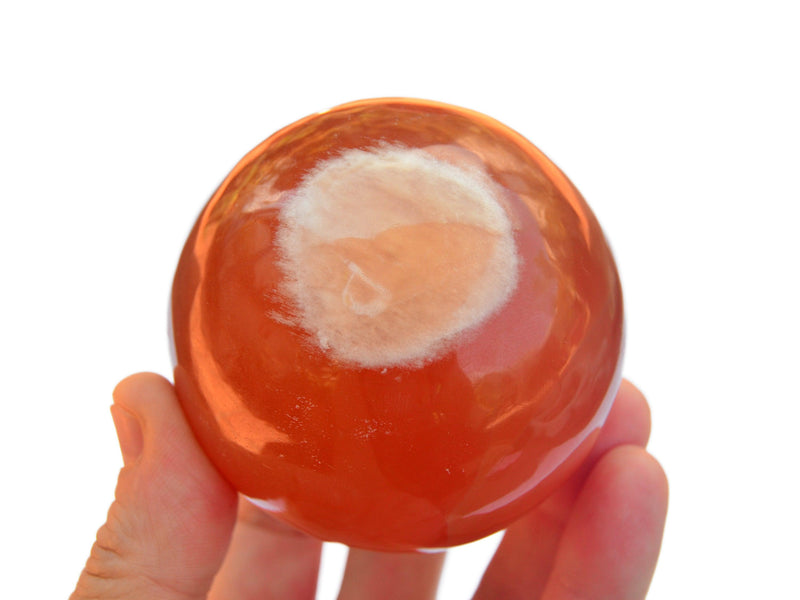 One honey calcite crystal sphere 70mm on hand with white background