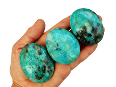 Three amazonite palmstone crystals on hand with white background