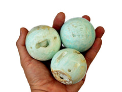 Three caribbean calcite crystal spheres 50mm-60mm on hand with white background