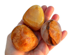 Three chunky yellow hematoid quartz tumbled stones on hand with white background