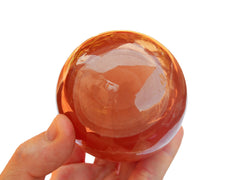 One large honey calcite crystal sphere 70mm on hand with white background