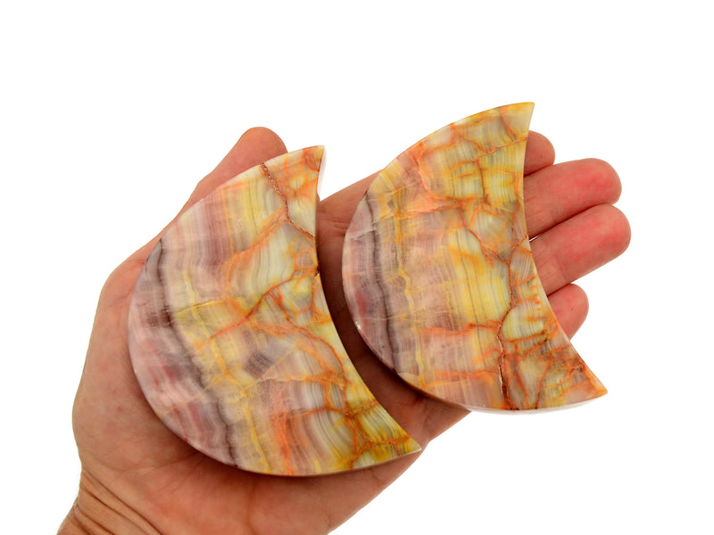 Two pink banded onyx moon stones 80mm on hand with white background