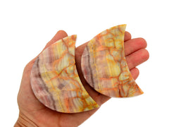 Two pink banded onyx moon stones 80mm on hand with white background