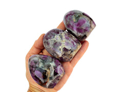 Three purple amethyst free form crystals 70mm on hand with white background