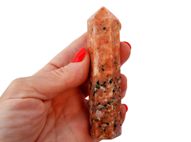 One orange calcite crystal tower point 90mm on hand
