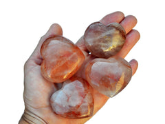 Four fire quartz heart carved minerals 55mm on hand with white background