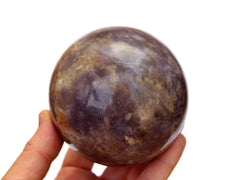 Large lepidolite crystal sphere 75mm on hand with white background