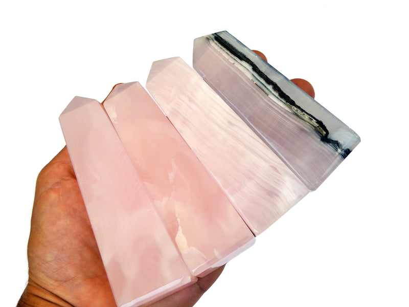 Four pink mangano calcite towers 90mm on hand with white background