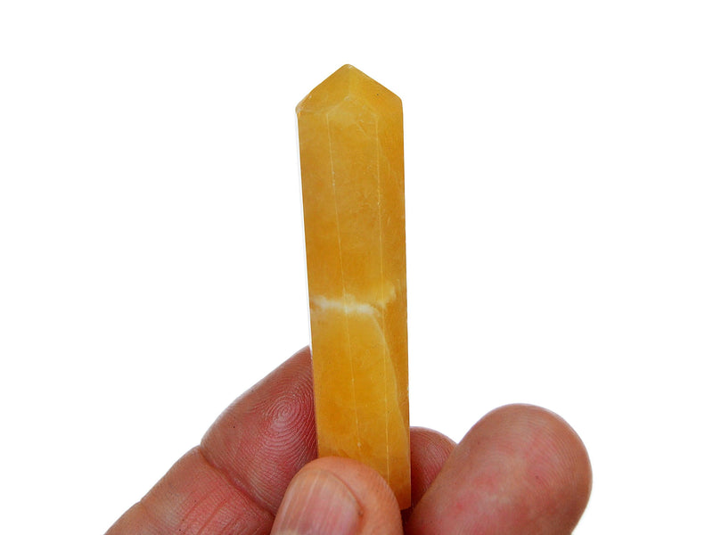 One mini orange calcite tower crystal on hand with white background